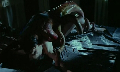 Screenshot from Possession - white woman writes beneath tentacle monster. Most of the image is in shadow